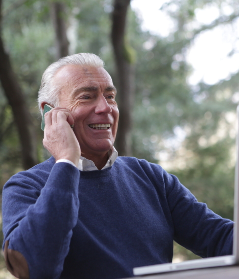 A happy older man talking on the phone while on a telephone consultation with Real Life Legacy